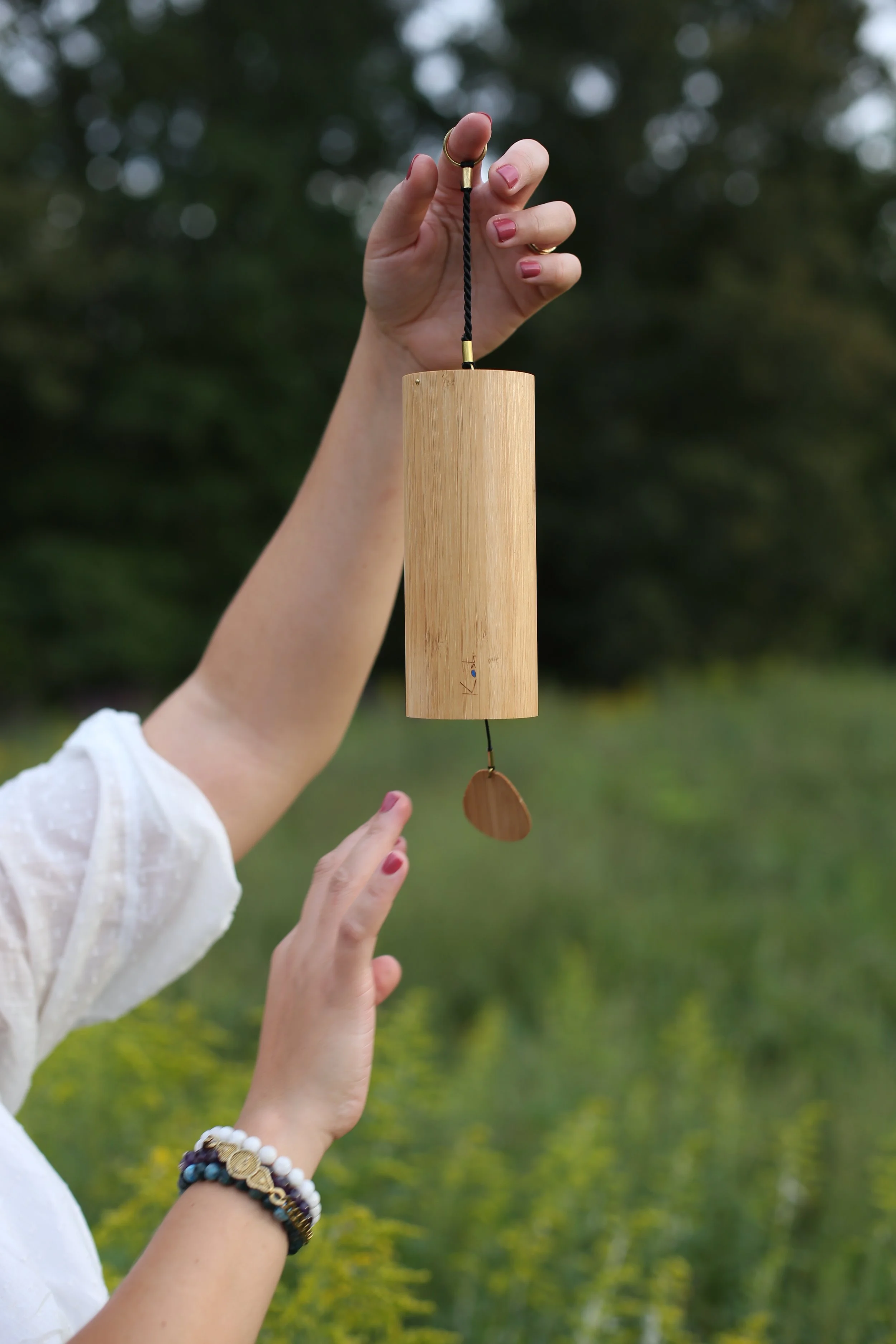 woman's hands holding and playing elemental Koshi chime outside