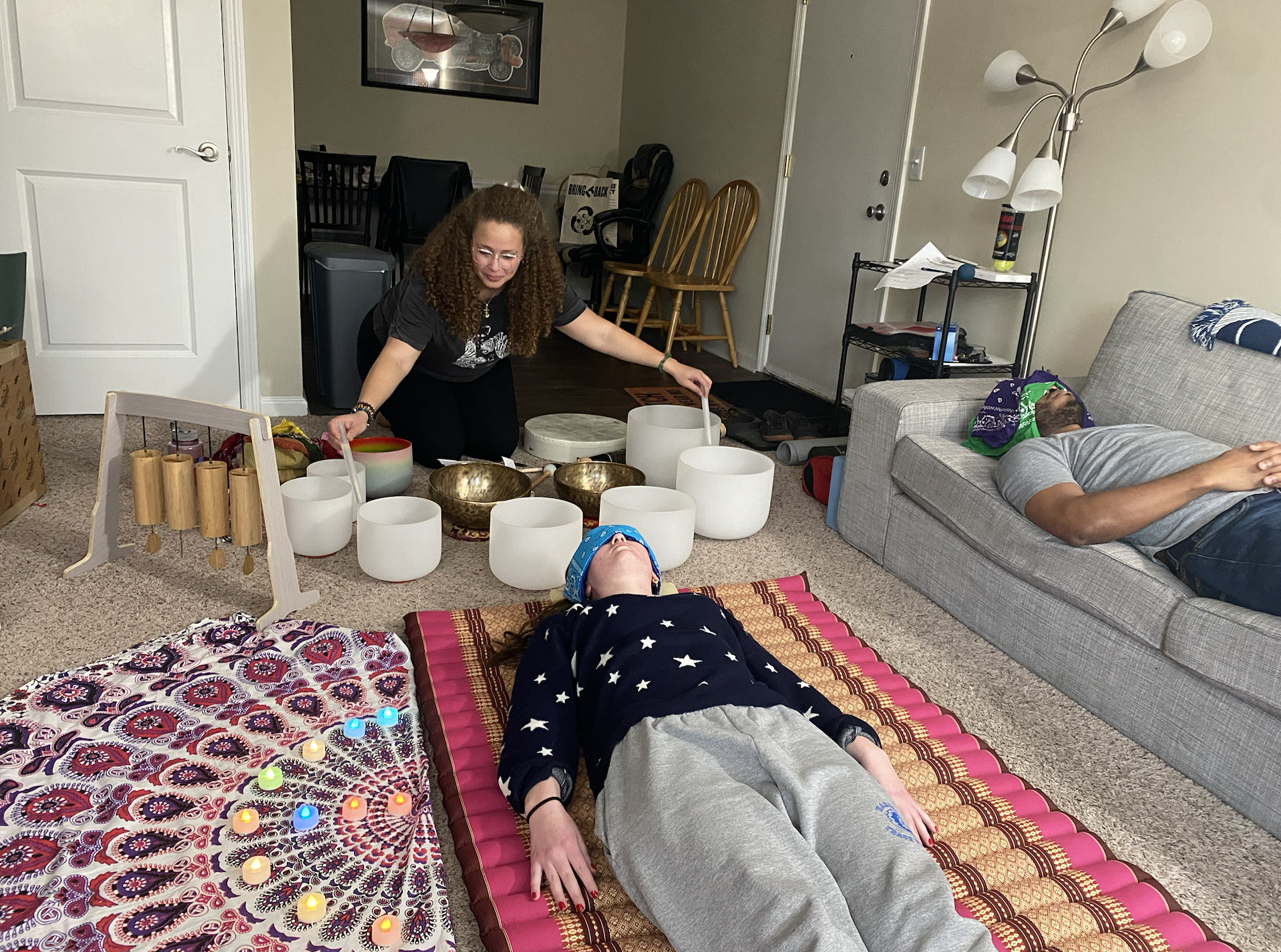 man on couch and woman on kapok mat receiving soundbath