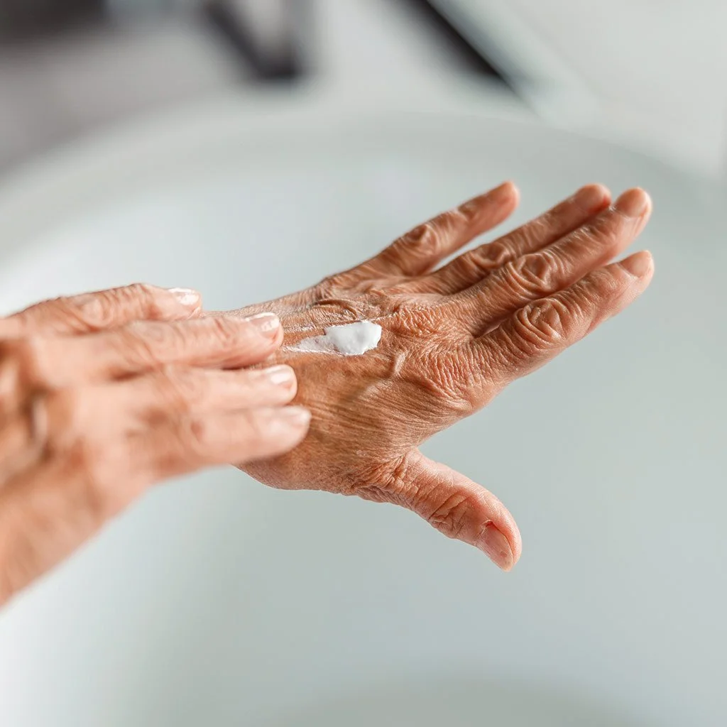 elderly person applying lotion to hands