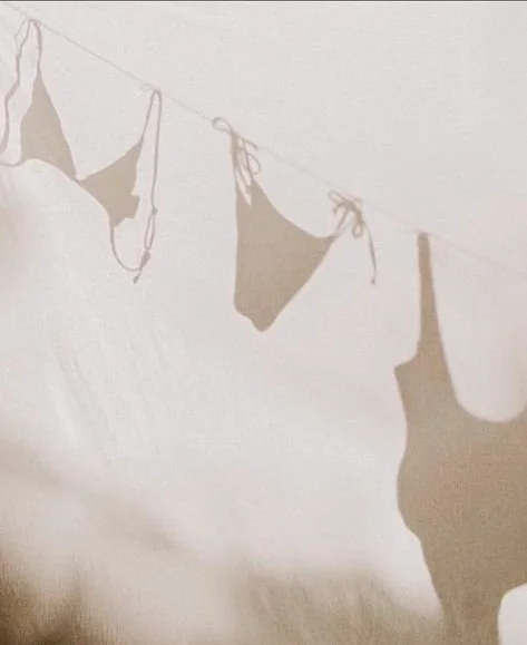 Clothes hanging on a string, creating shadows on a white wall.