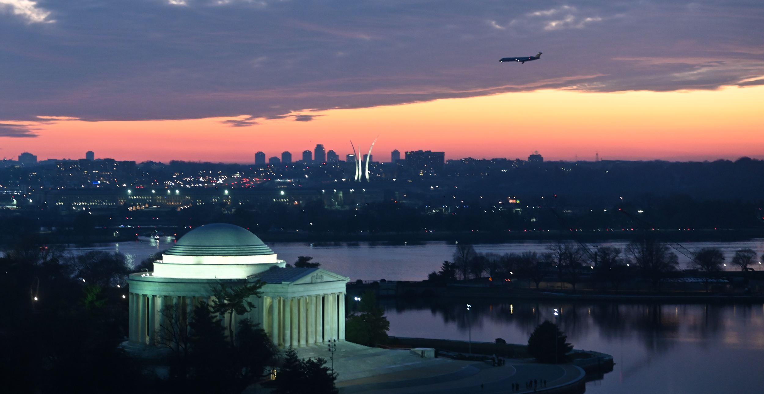 image of plane landing with the Air Force memorial in the background