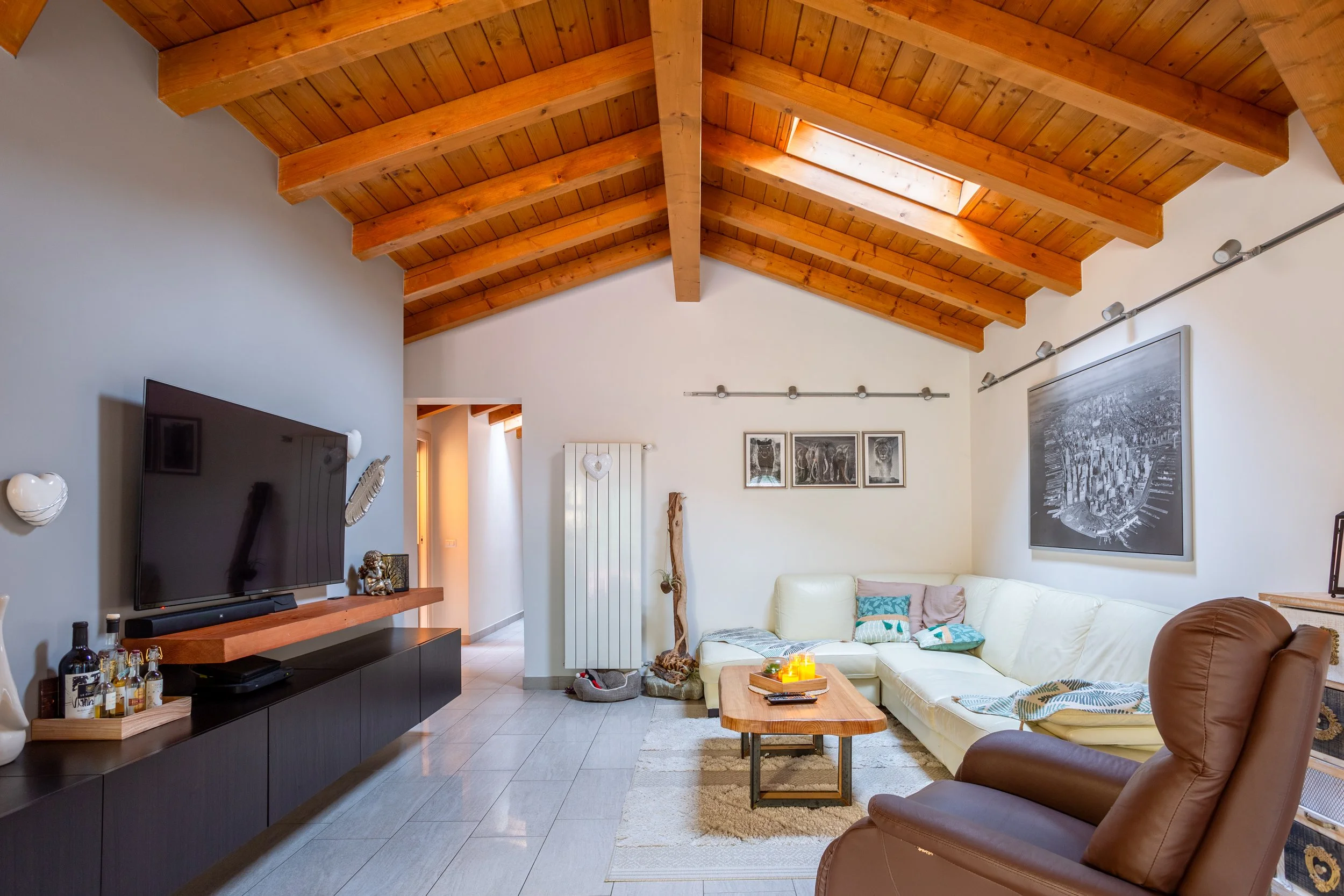 Fotografia professionale di un attico con soffitto in legno in provincia di Varese. L'immagine è curata nella disposizione degli arredi e nell'inquadratura perfetta. Riprende uno spazio moderno e minimale.