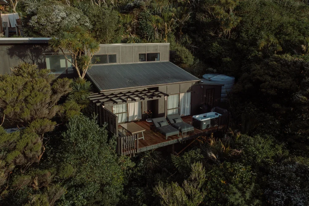 A modern house with a rooftop deck and enjoying a view surrounded by dense green trees and shrubs.