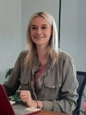 A young woman with blonde hair smiling during a meeting or office setting