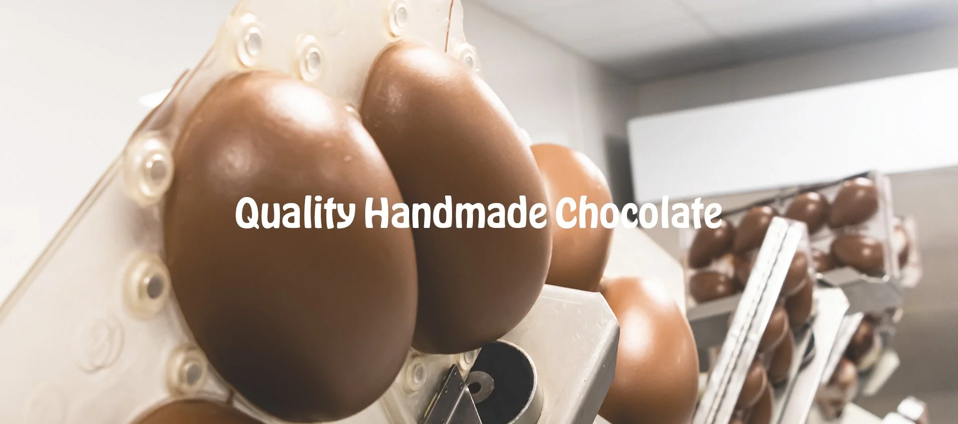 Close-up of chocolate easter eggs in a manufacturing facility with the text 'Delivering Quality Handcrafted Chocolate' overlaid.