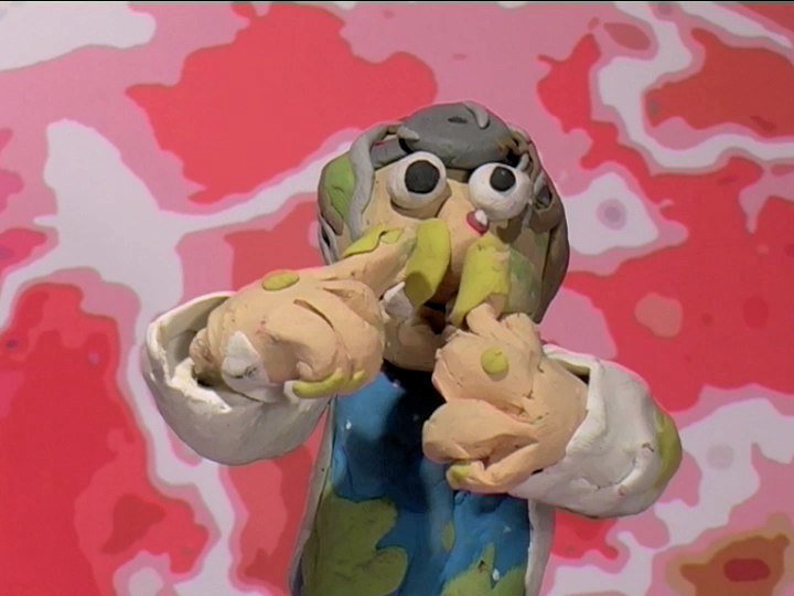 A colorful clay sculpture of a girl with gray hair and large eyes, holding two small rabbits, set against a pink and red abstract background.