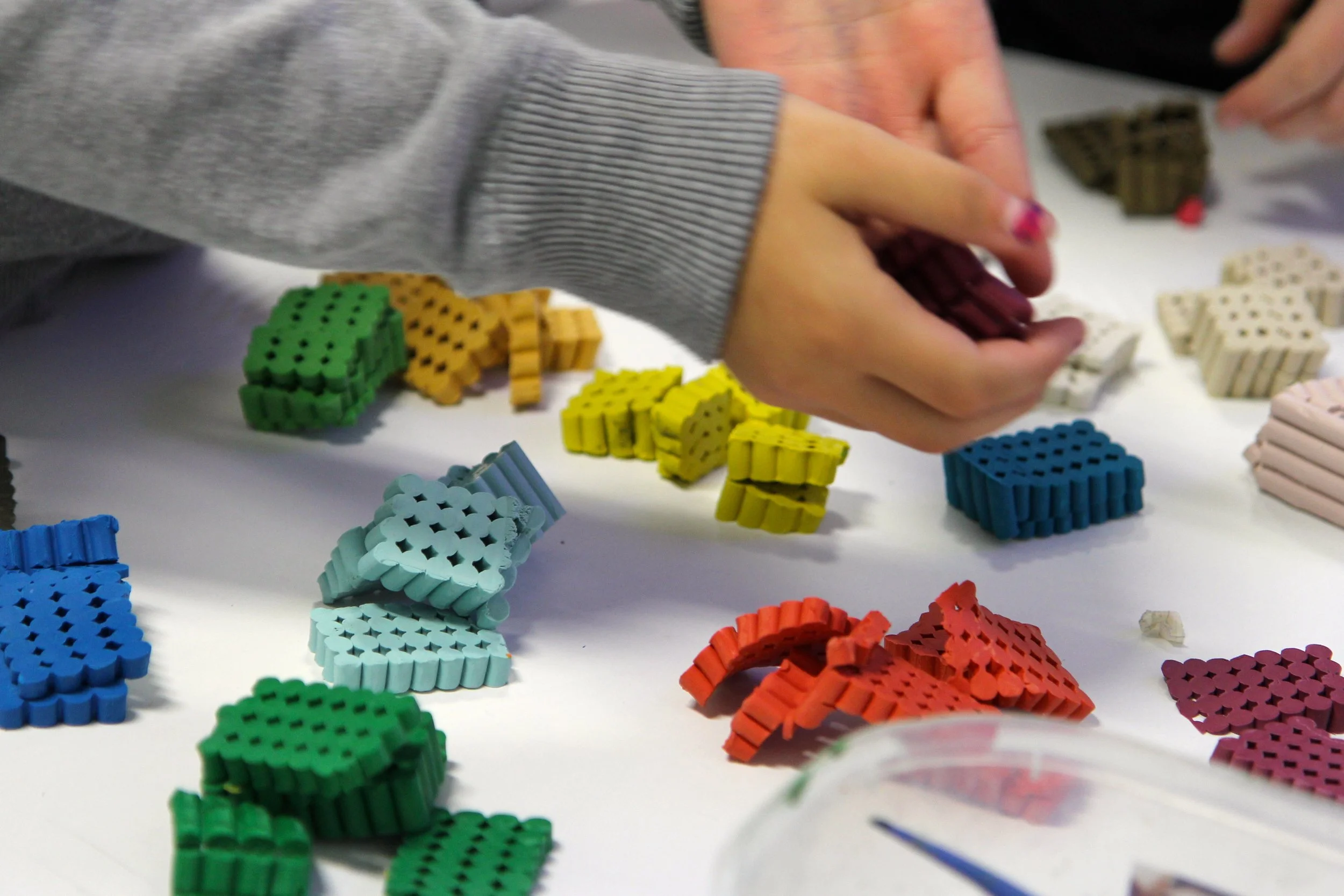 Person sorting colorful domino pieces on a white table.