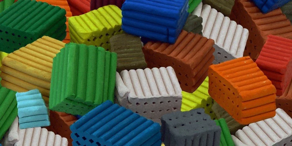 Close-up of colorful Lego bricks in various colors including green, yellow, blue, white, gray, orange, red, and brown.
