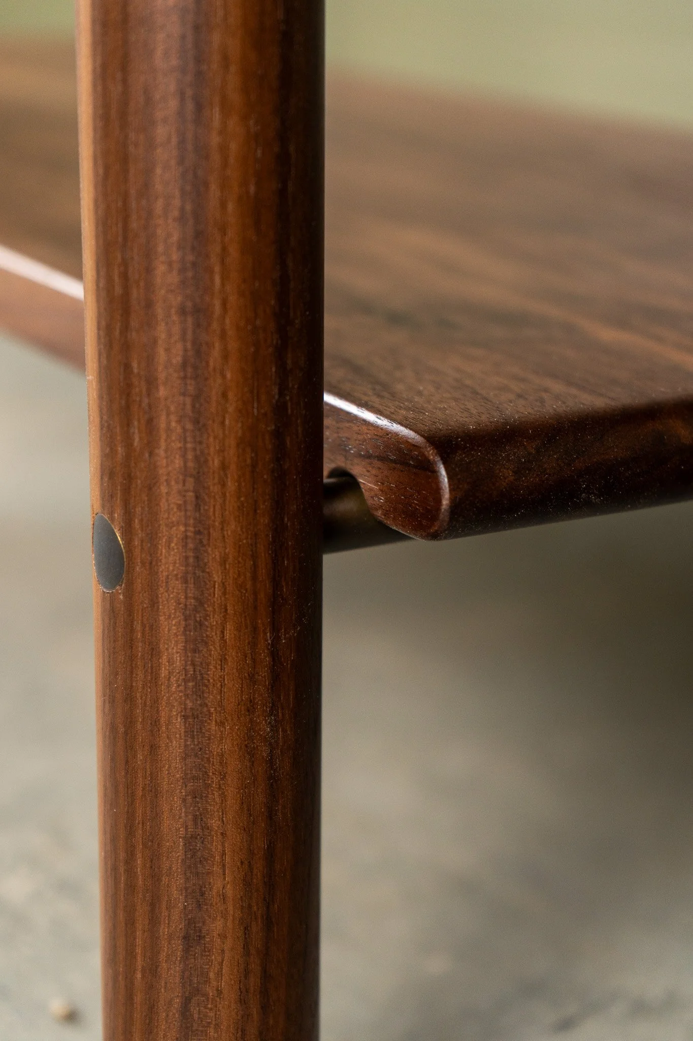 Close-up of a wooden table or furniture piece showing the edge and a vertical wooden support with visible wood grain.