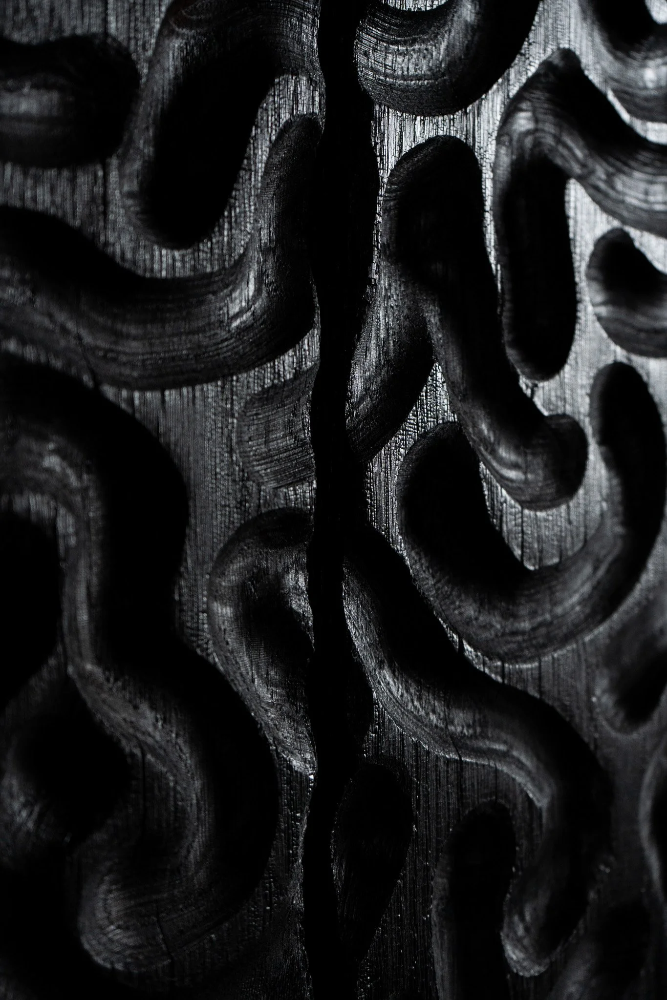 Hand carved solid Oak artwork wall panel. Carving pattern has variable grooves cut in curved patterns. The sculptural piece has been charred with a yakisugi or sho sugi ban finish that’s jet black. Artwork shown on an olive green wall.