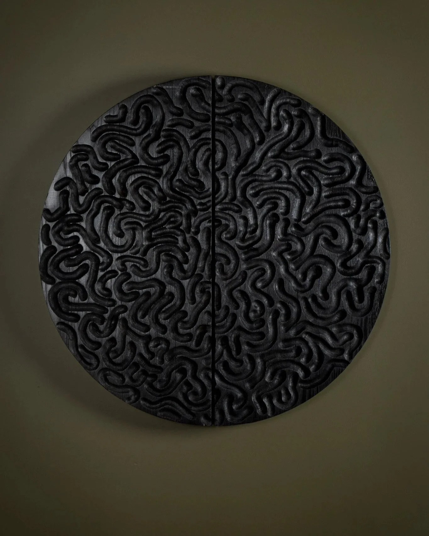 Hand carved solid Oak artwork wall panel. Carving pattern has variable grooves cut in curved patterns. The sculptural piece has been charred with a yakisugi or sho sugi ban finish that’s jet black. Artwork shown on an olive green wall.