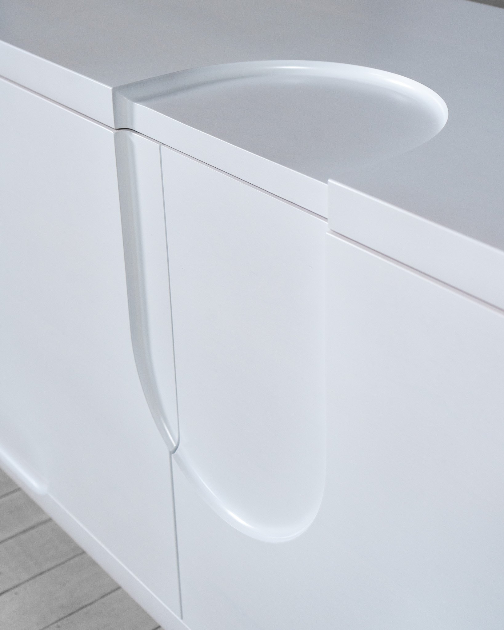 Close-up of a white cabinet with a rounded silver handle.