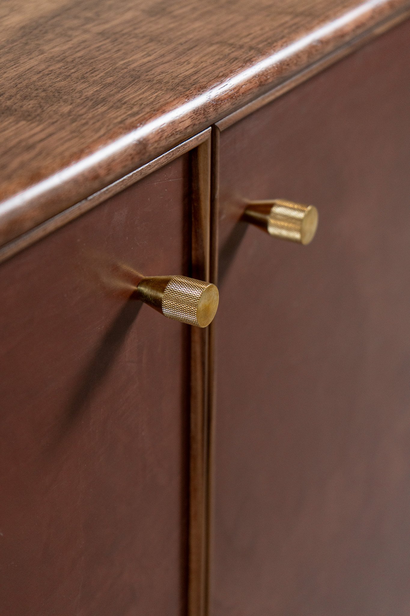 Close-up of a wooden surface with brass-colored knobs on a furniture piece.