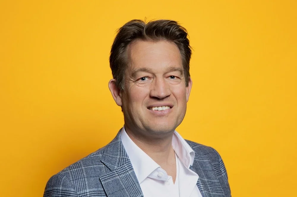 Man in pak voor een gele achtergrond