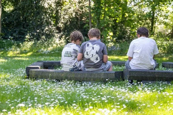 Drie kinderen op een bankje in de natuur