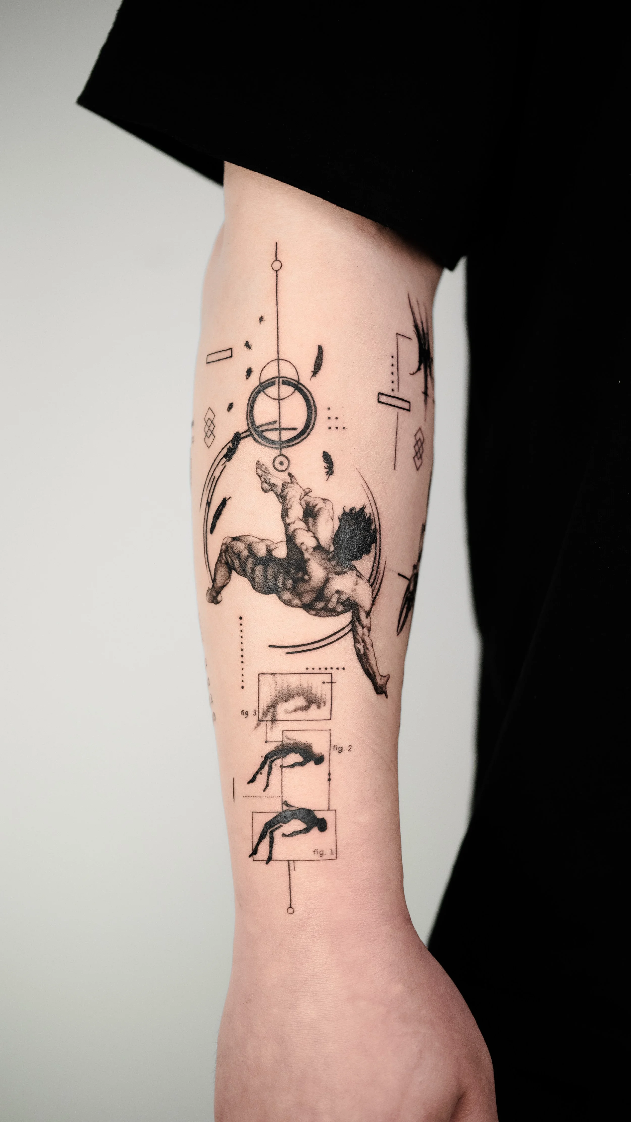 Tattoo of a human figure in a diving or leaping pose, accompanied by geometric shapes, lines, and technical diagrams on a person's upper arm.