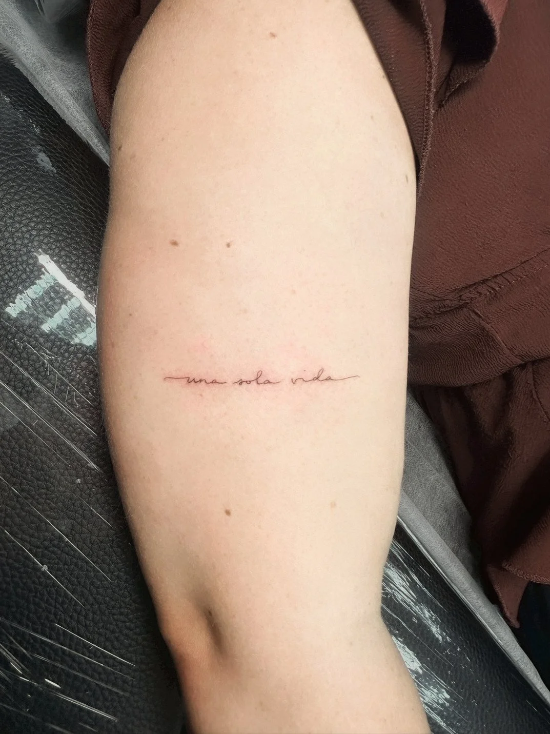 Tattoo on person's thigh with the phrase 'una sola vida' written in cursive script.