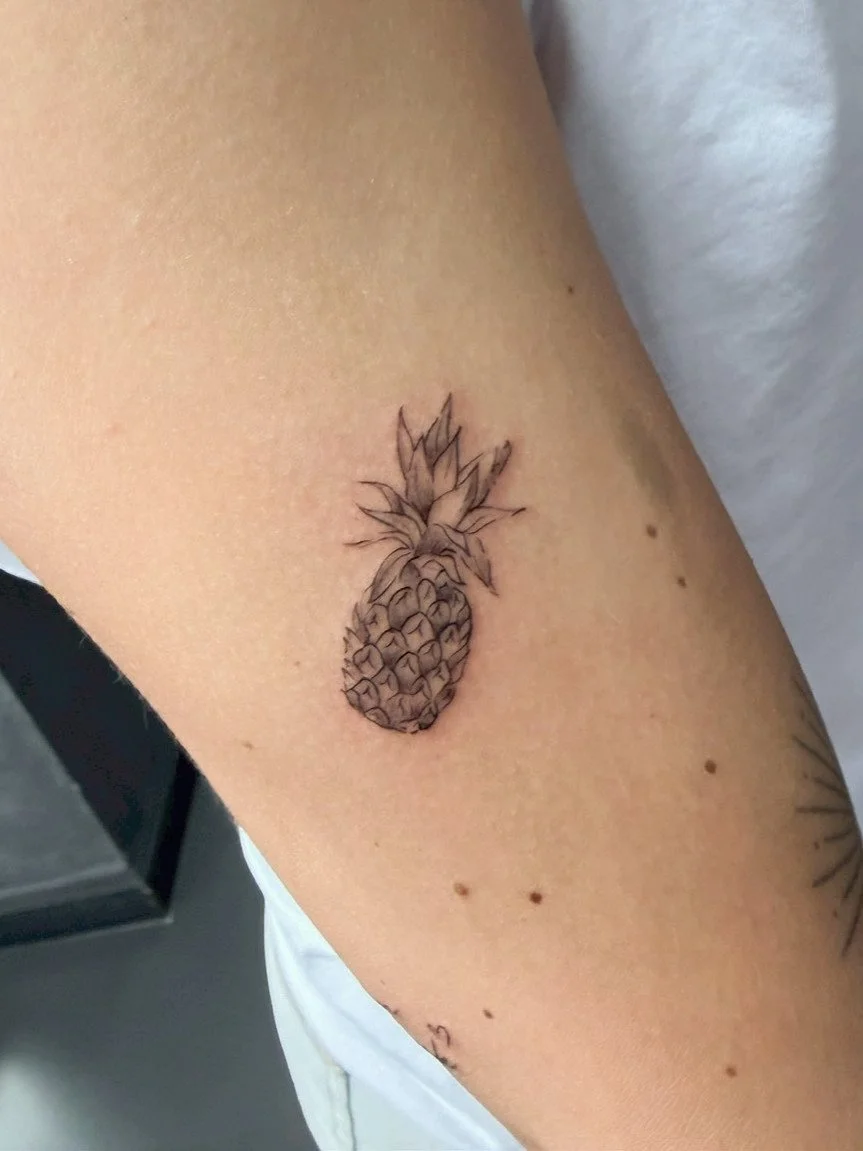 Tattoo of a pineapple on a person's arm.