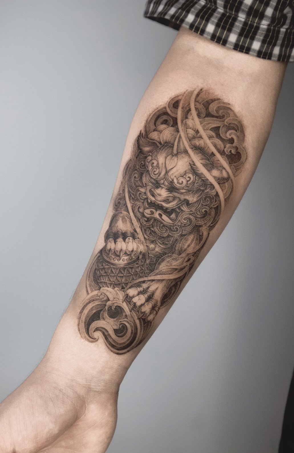 Tattoo of a detailed traditional dragon on a person's forearm, with intricate shading and swirling clouds.