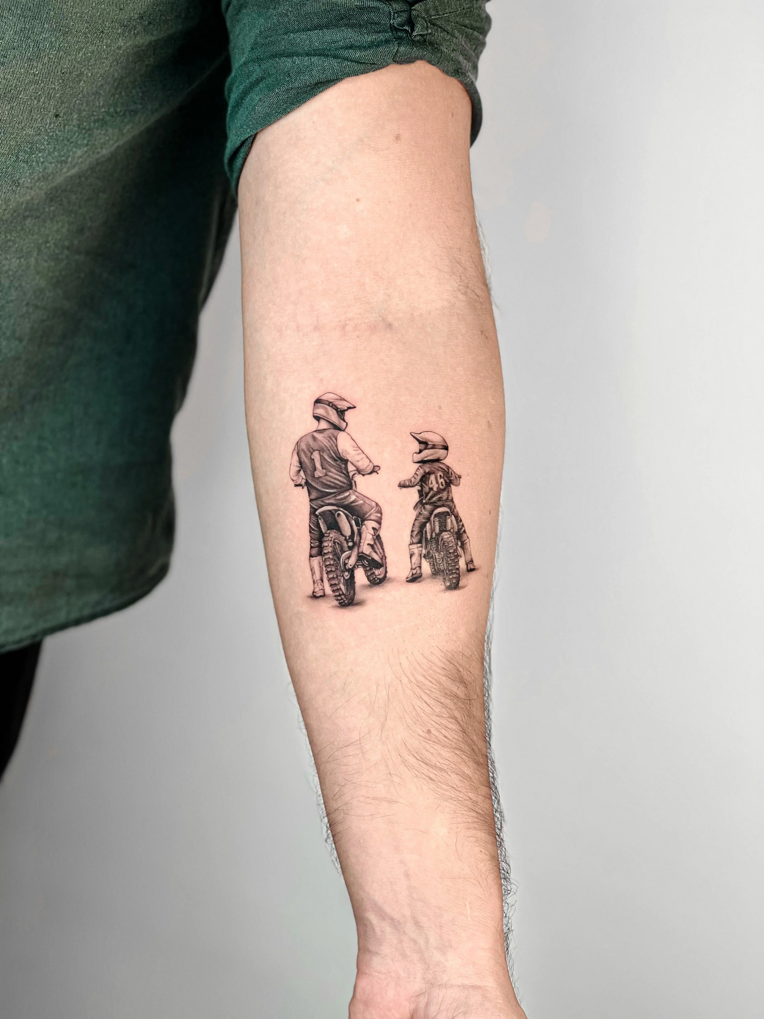 Tattoo of two motorcyclists wearing helmets on a person's arm.
