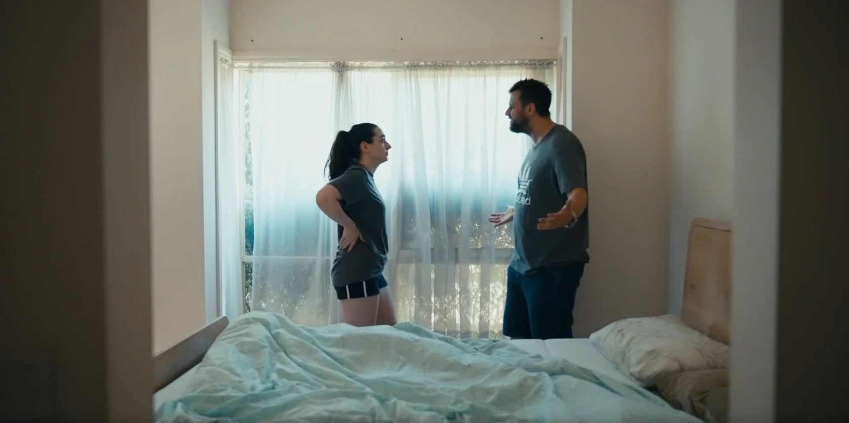 A man and woman having an argument in a bedroom.
