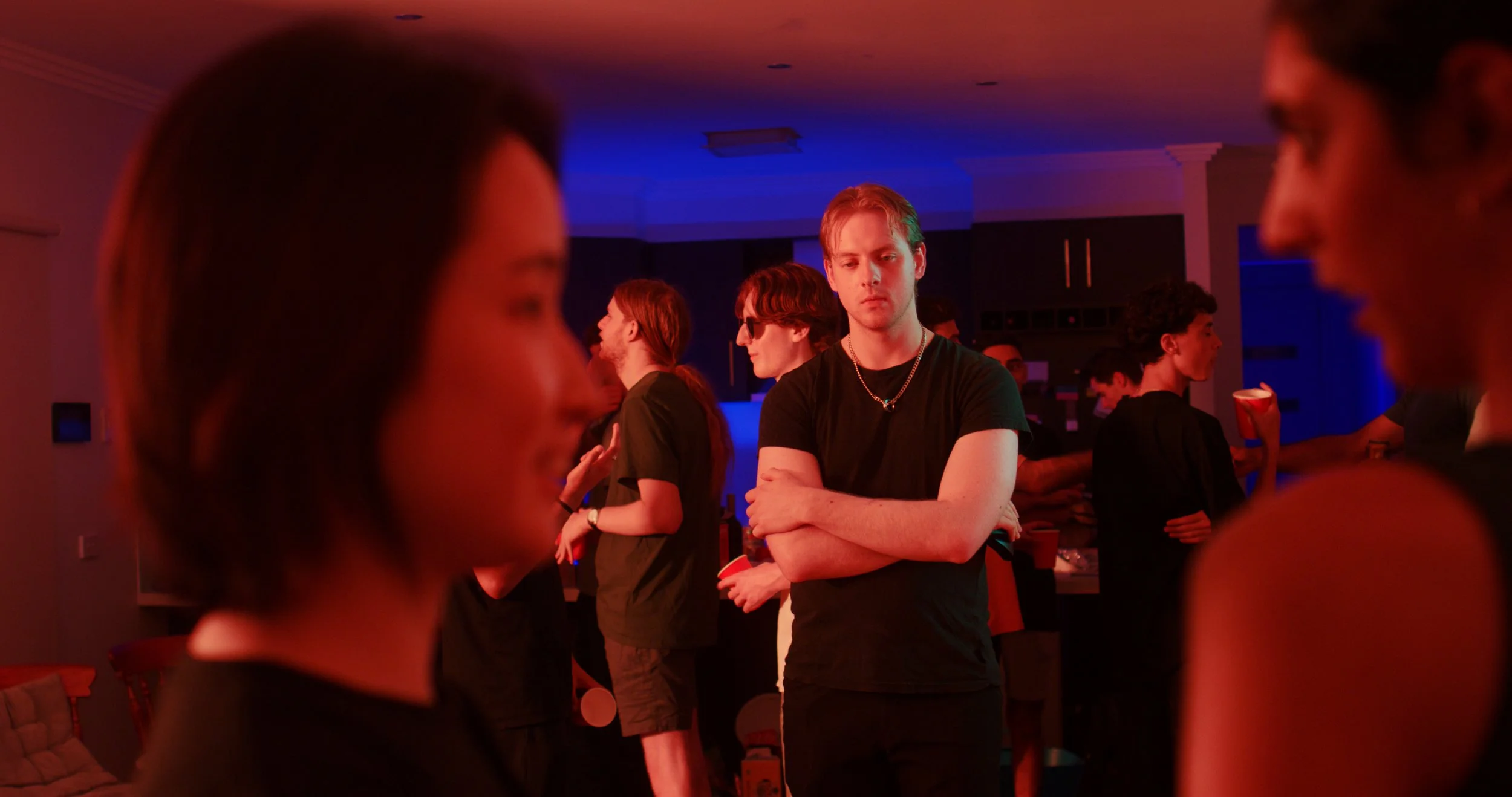 People socializing at a party with ambient red and blue lighting.