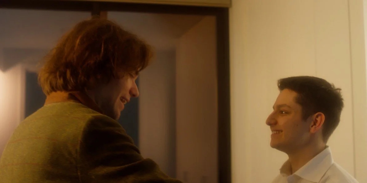 Two people smiling and shaking hands indoors.