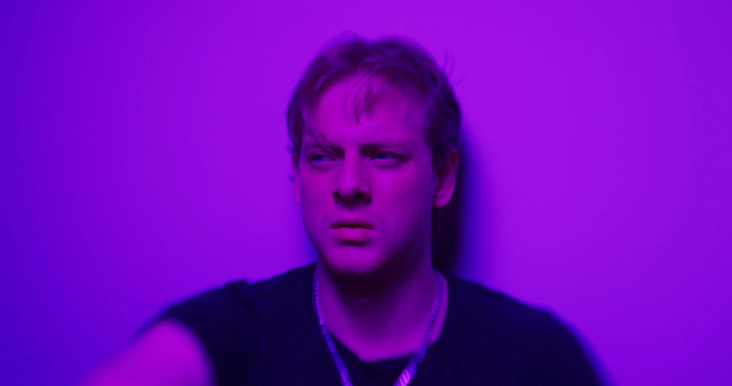 Person with a contemplative expression under purple lighting