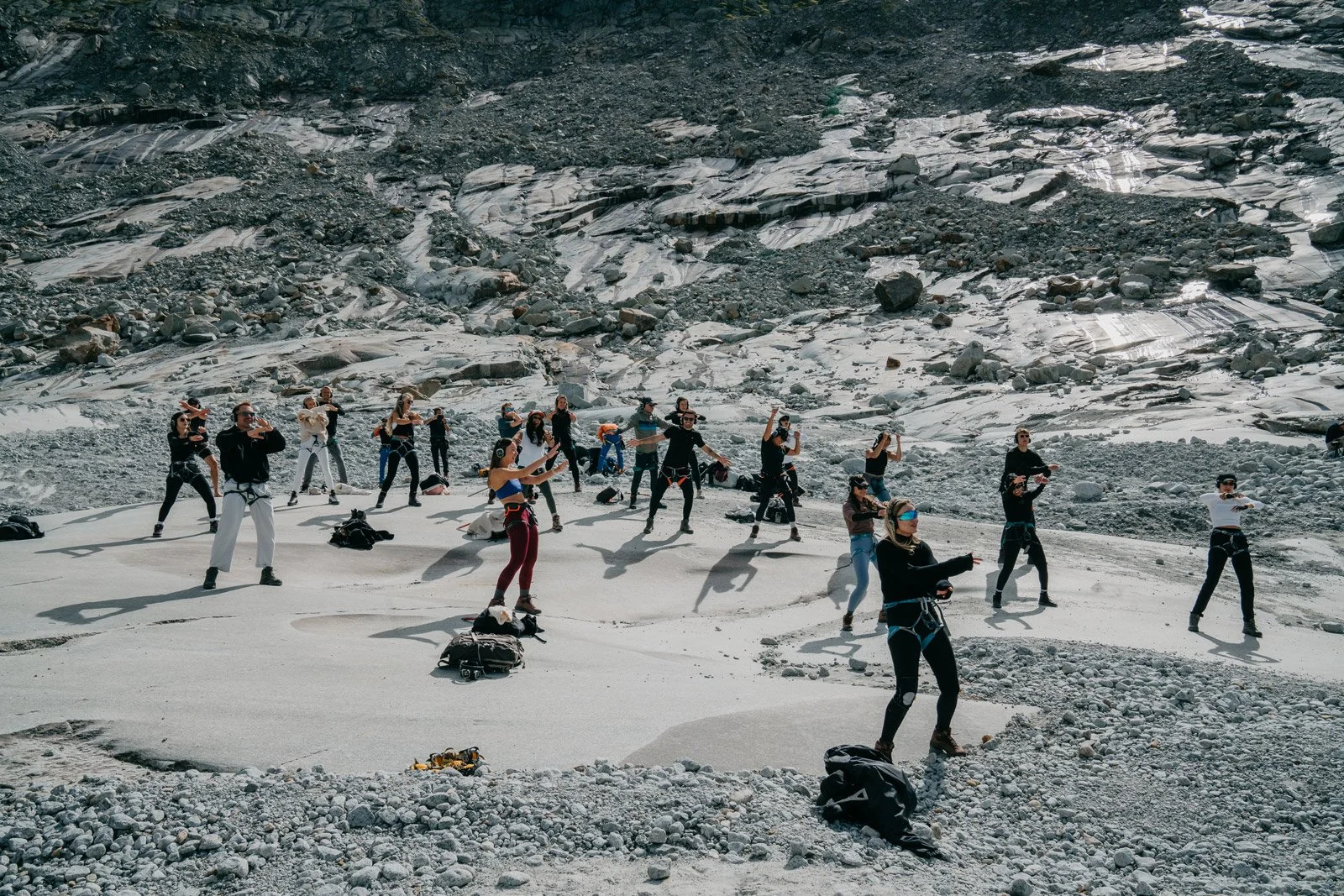 Groupe de personnes en tenue de sport pratiquant une activité physique sur un paysage de glacier ou de terrain montagneux rocheux.