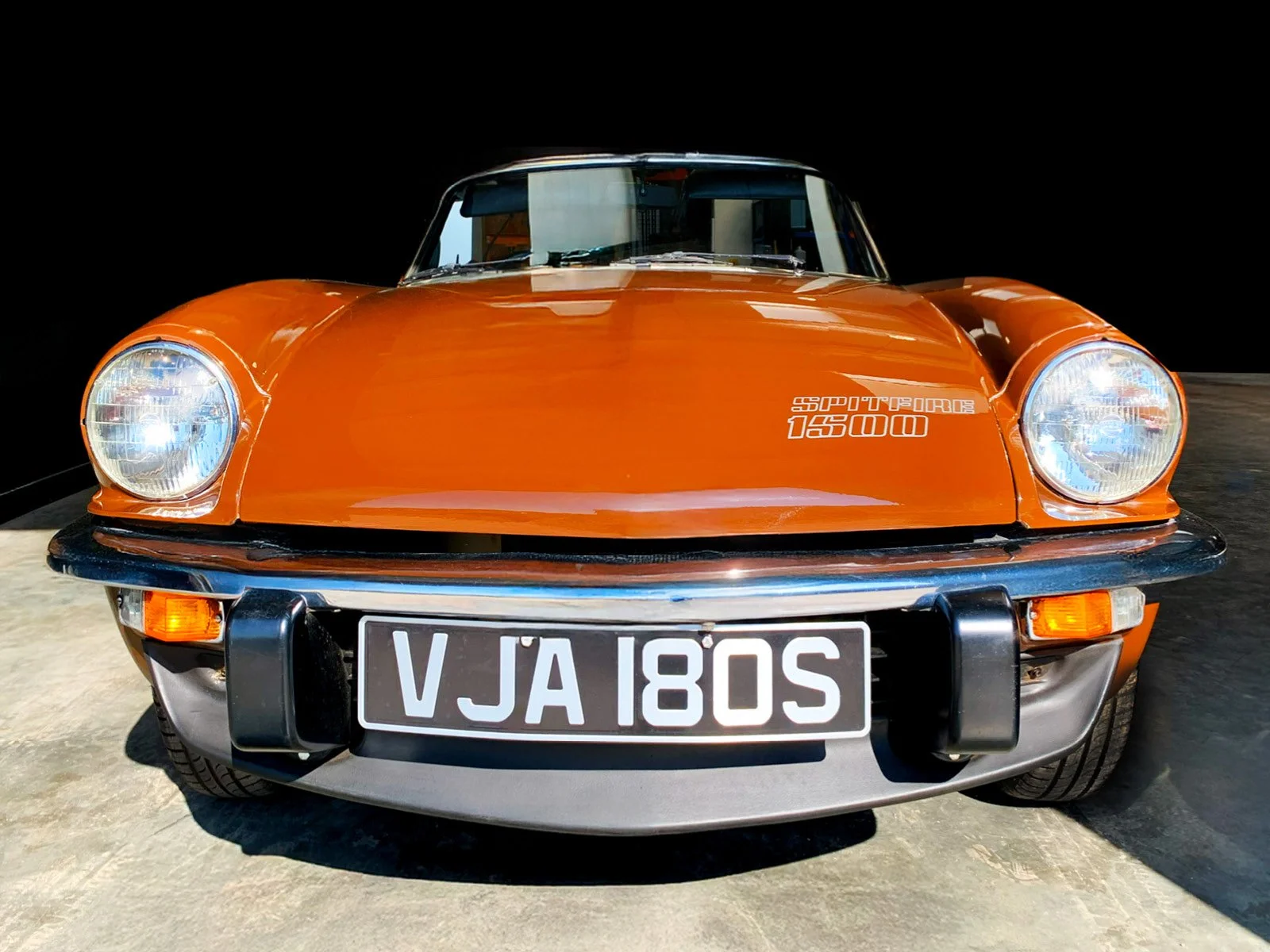 Front view of a vintage orange sports car with a black bumper and a black license plate that reads VJA 180S, with the words 'SPORTFORCE 1500' on the hood.