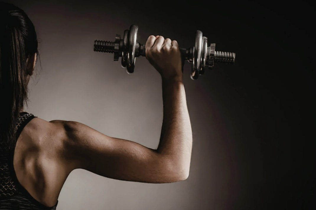 Back view of woman holding dumbbell