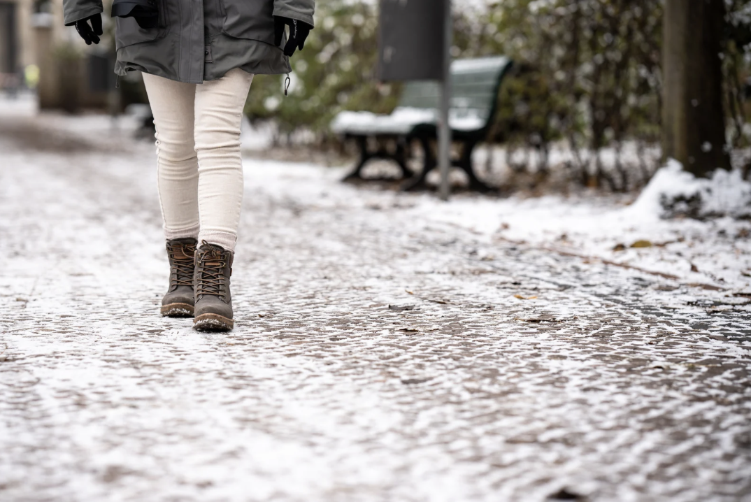 woman's legs walking on snowy sidewalk