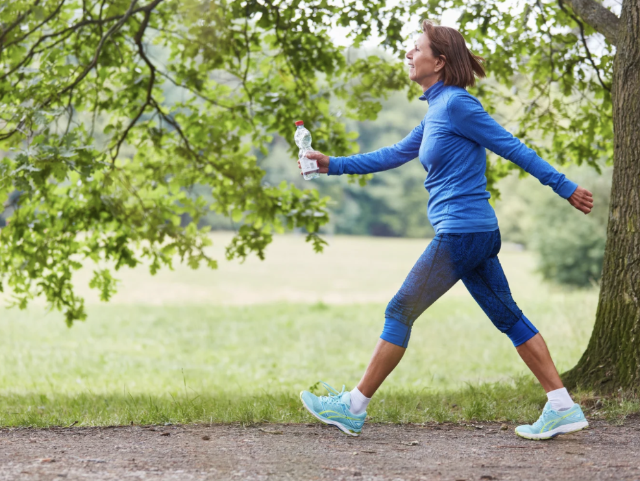 woman walking on path in park carrying water bottle