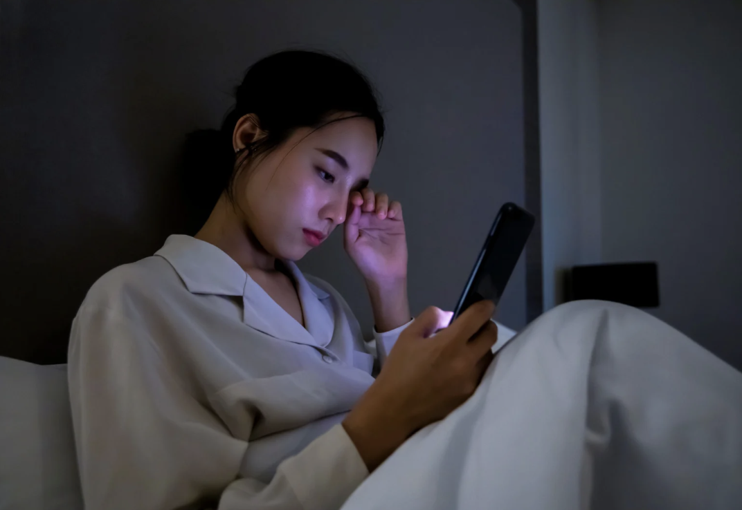 woman n bed looking at phone
