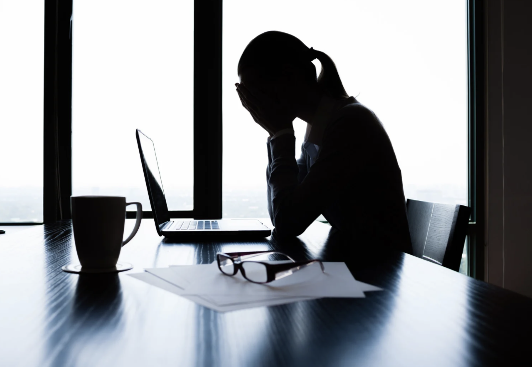 silhouette woman holding head at computer