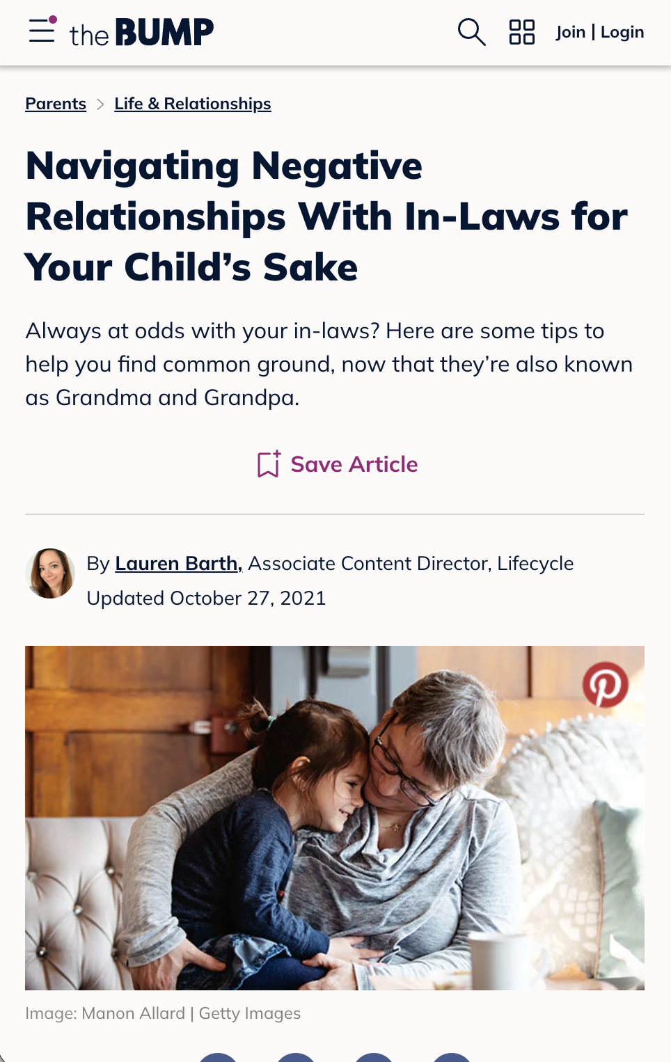 A grandmother hugging a young girl while sitting on a beige couch. The grandmother has short gray hair and glasses, and the girl has long brown hair tied back. They are smiling and close to each other, with a cozy home background.
