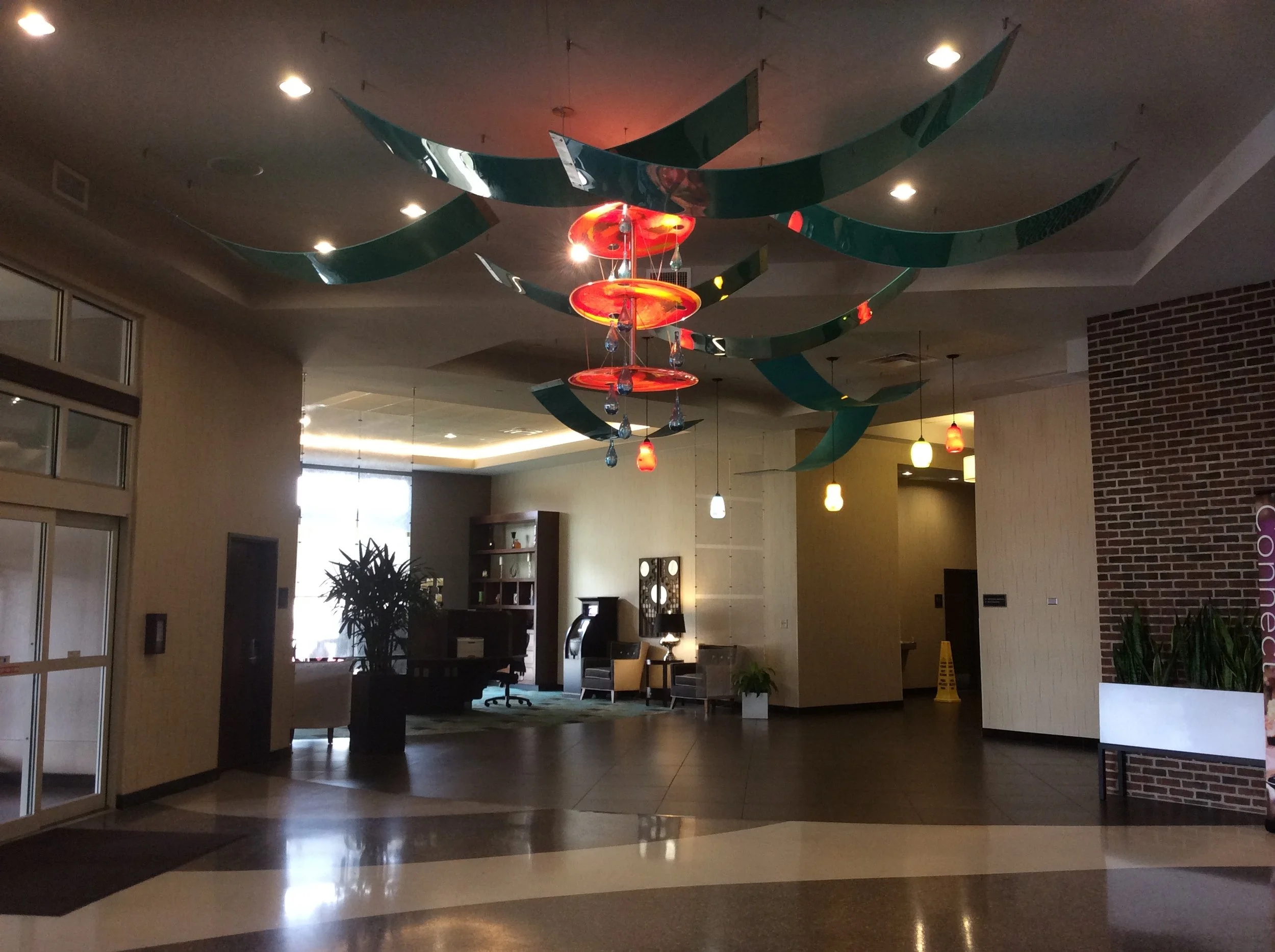 Colorful glass chandelier with tropical fruit and floral design, reflecting in a mirror on a wall.