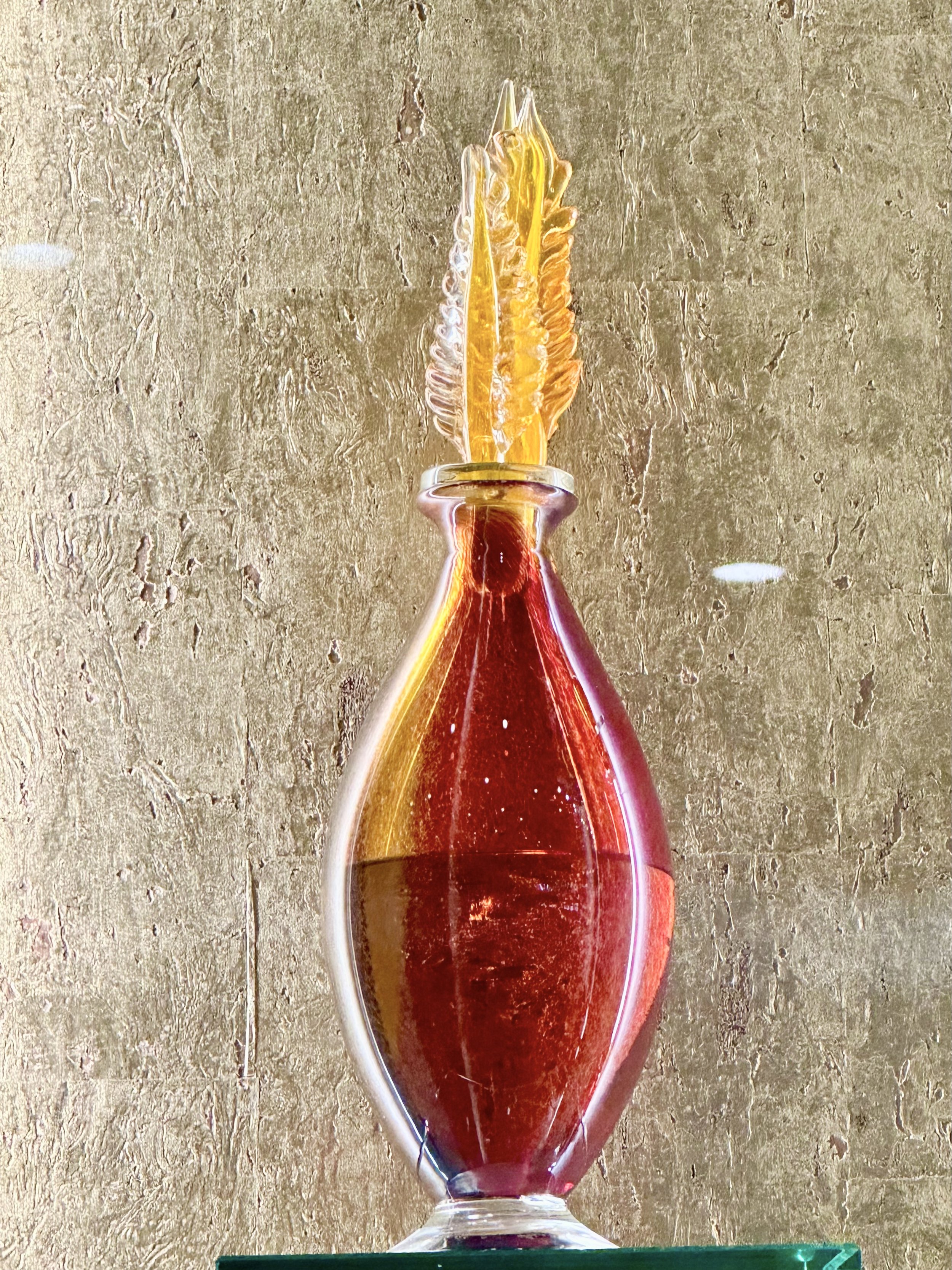 Colorful glass vase with a red and yellow pattern, topped with intricate yellow glass art.