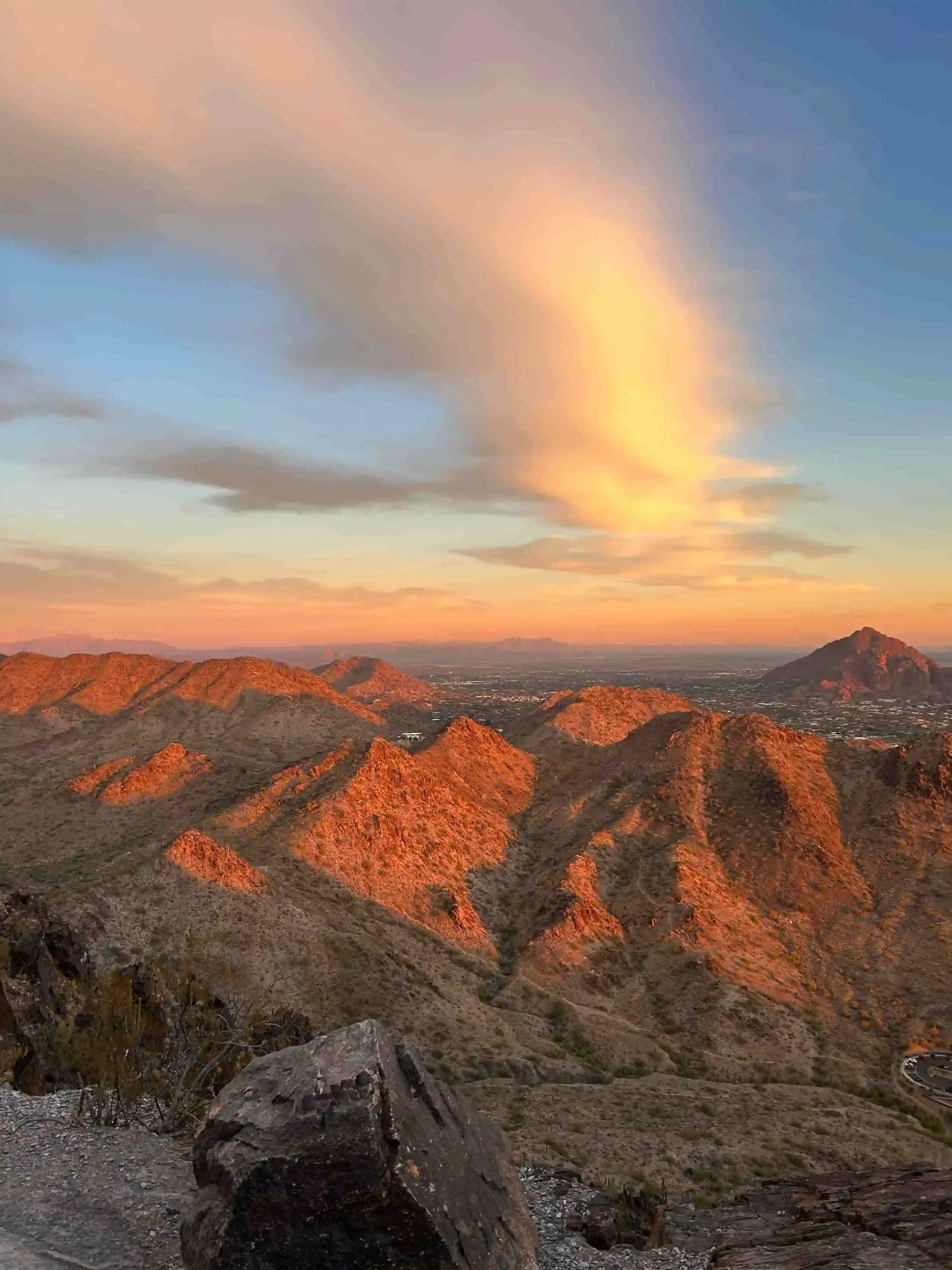 Sunset over desert mountain range with colorful clouds in the sky.