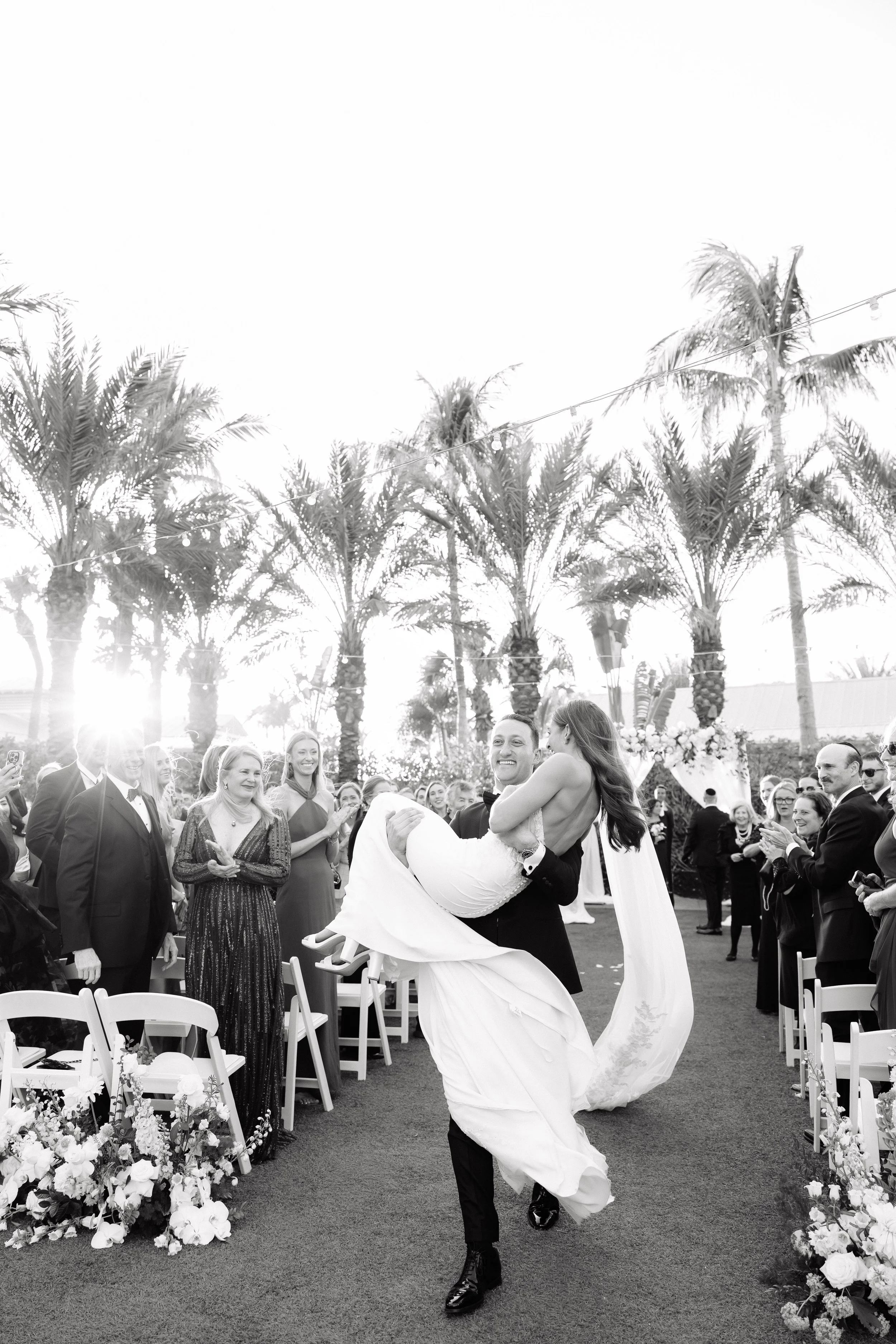 Groom carrying bride during recessional at Hyatt Regency Coconut Point Resort and Spa by Naples wedding photographer