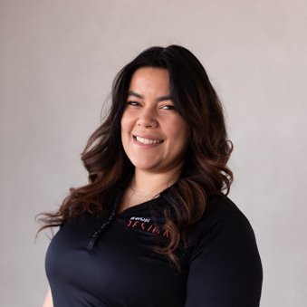 A woman with long wavy dark hair smiling and winking at the camera, wearing a black shirt.