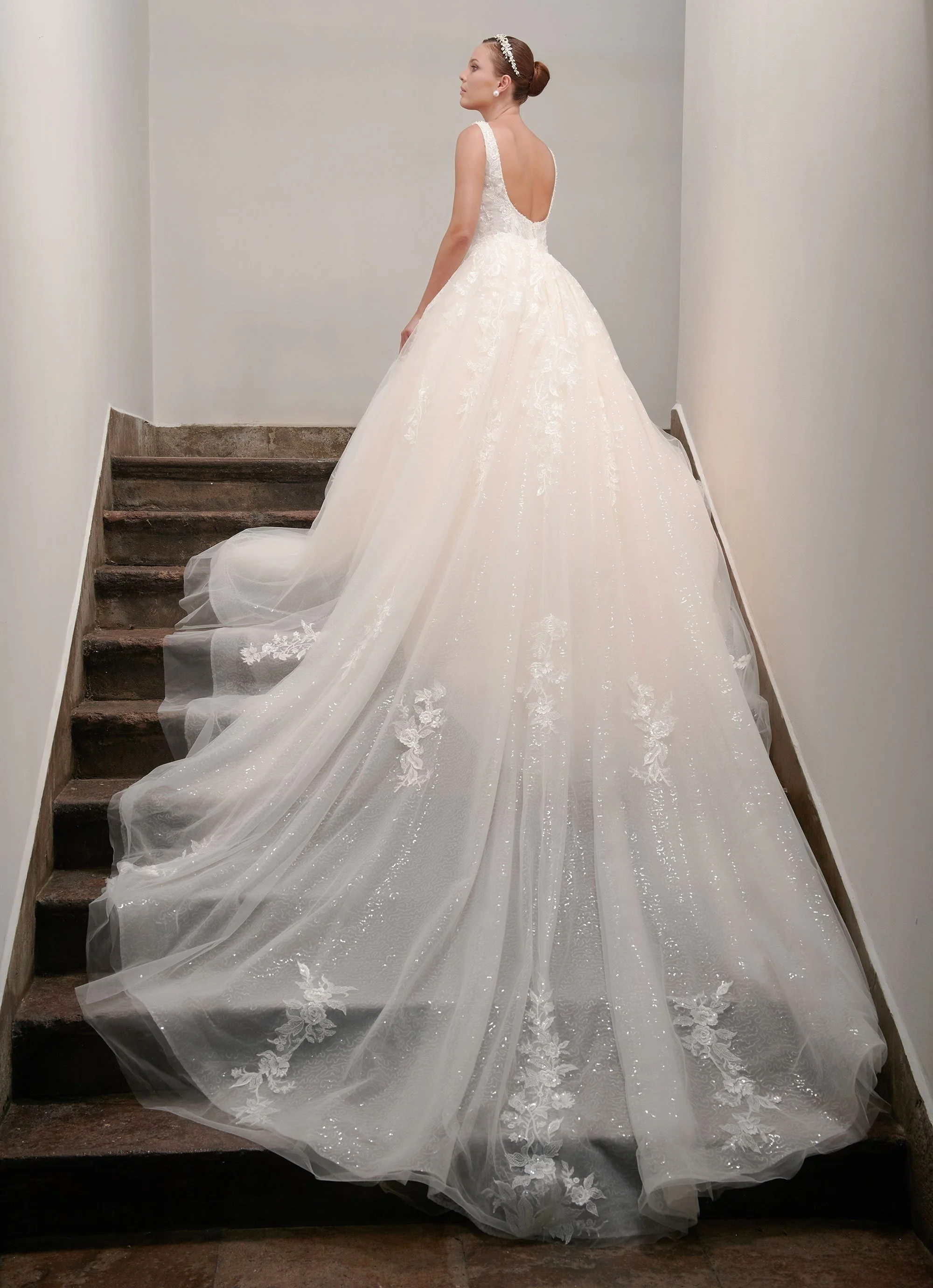 Espalda baja y redondeada del vestido de novia Candido con cola larga sobre escalera.