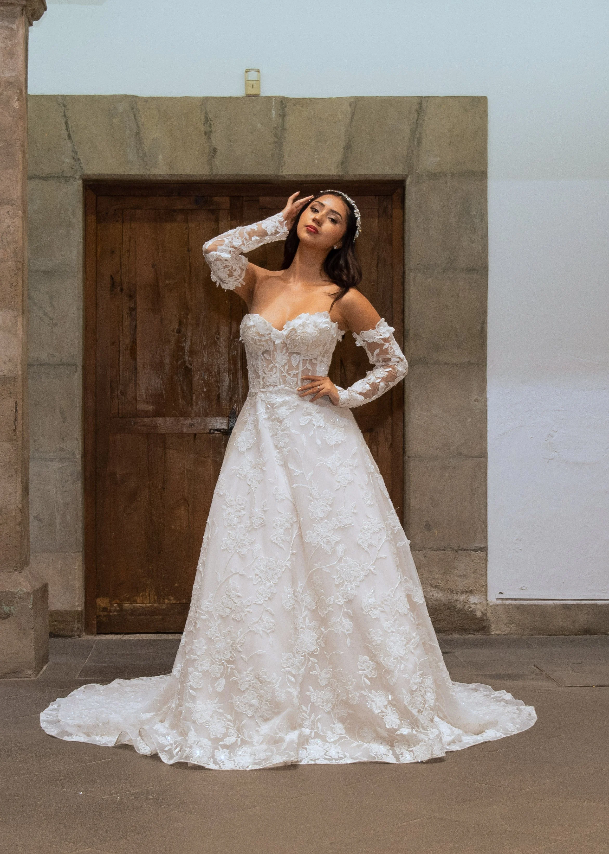 Vestido de novia Lucas de frente luciendo las mangas largas de encaje desmontables.