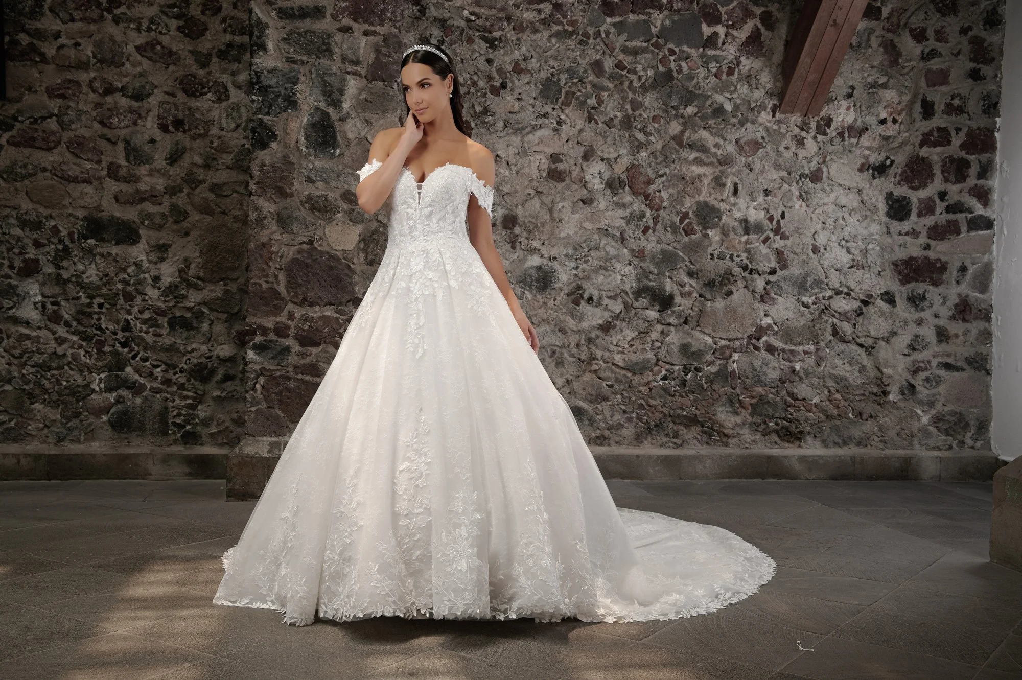 Novia con el vestido Camila de Bridenformal, princesa de tul con brillo y mangas caídas, vista frontal con cola.