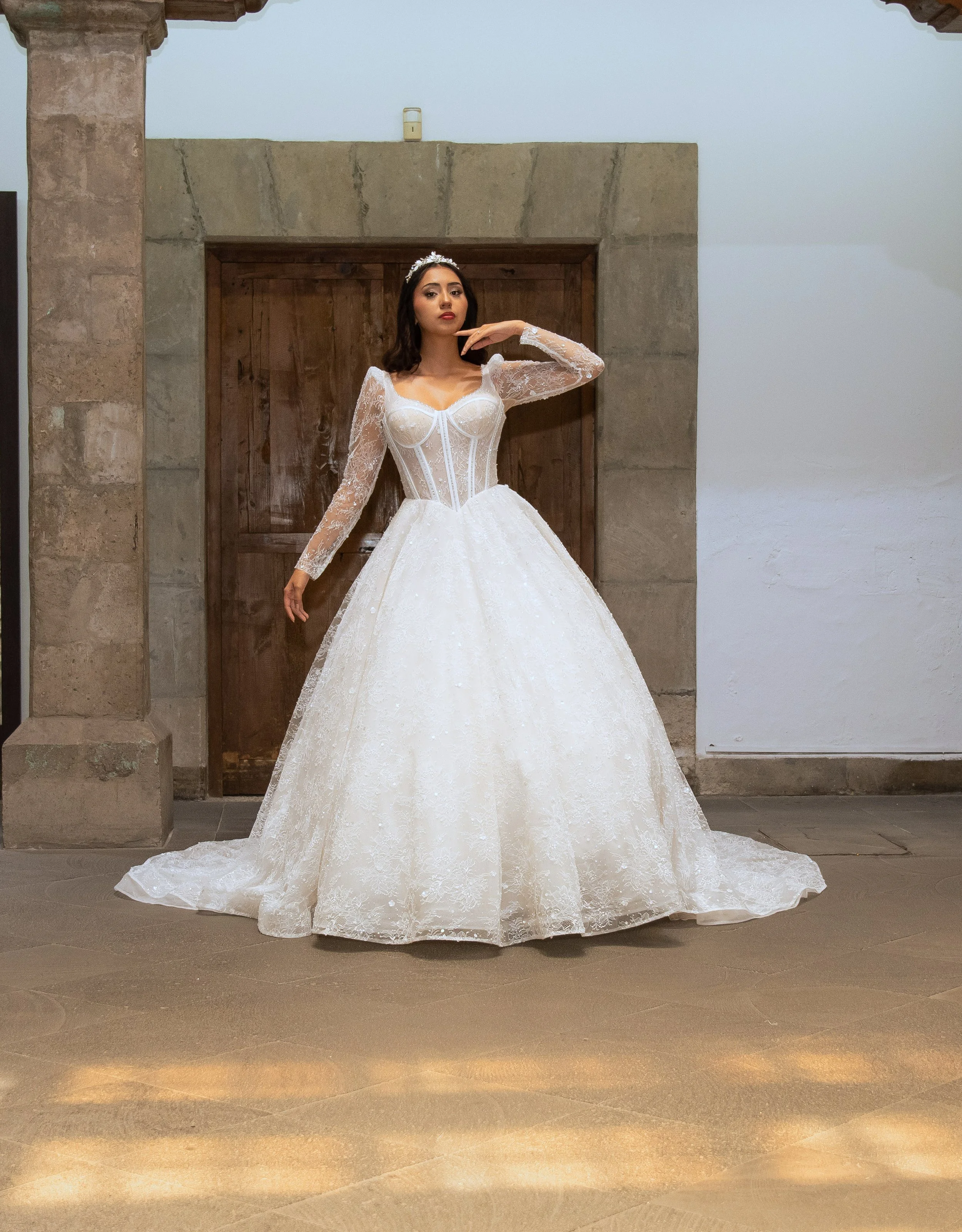 Novia con el vestido Luna de Bridenformal, silueta princesa con brillo y mangas largas de encaje, vista frontal completa.