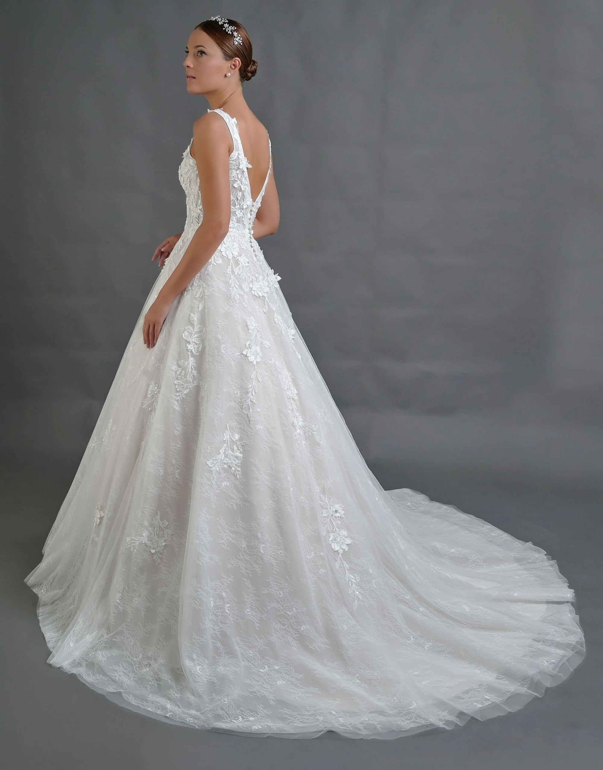 Espalda del vestido de novia Borbon con escote profundo en V y falda de tul con cola larga.