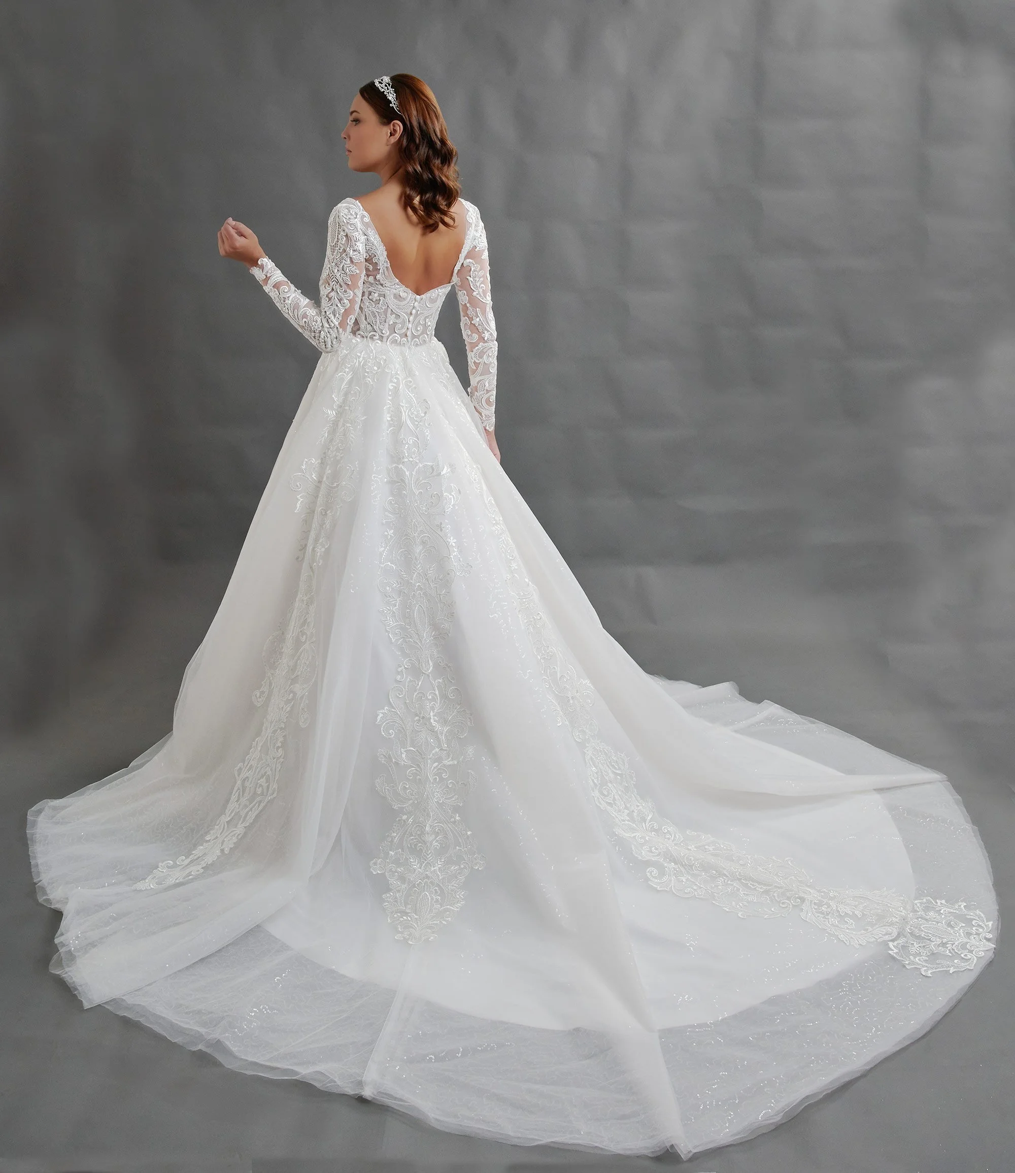 Espalda del vestido de novia Baltasar con mangas largas de encaje y falda de tul con cola larga.