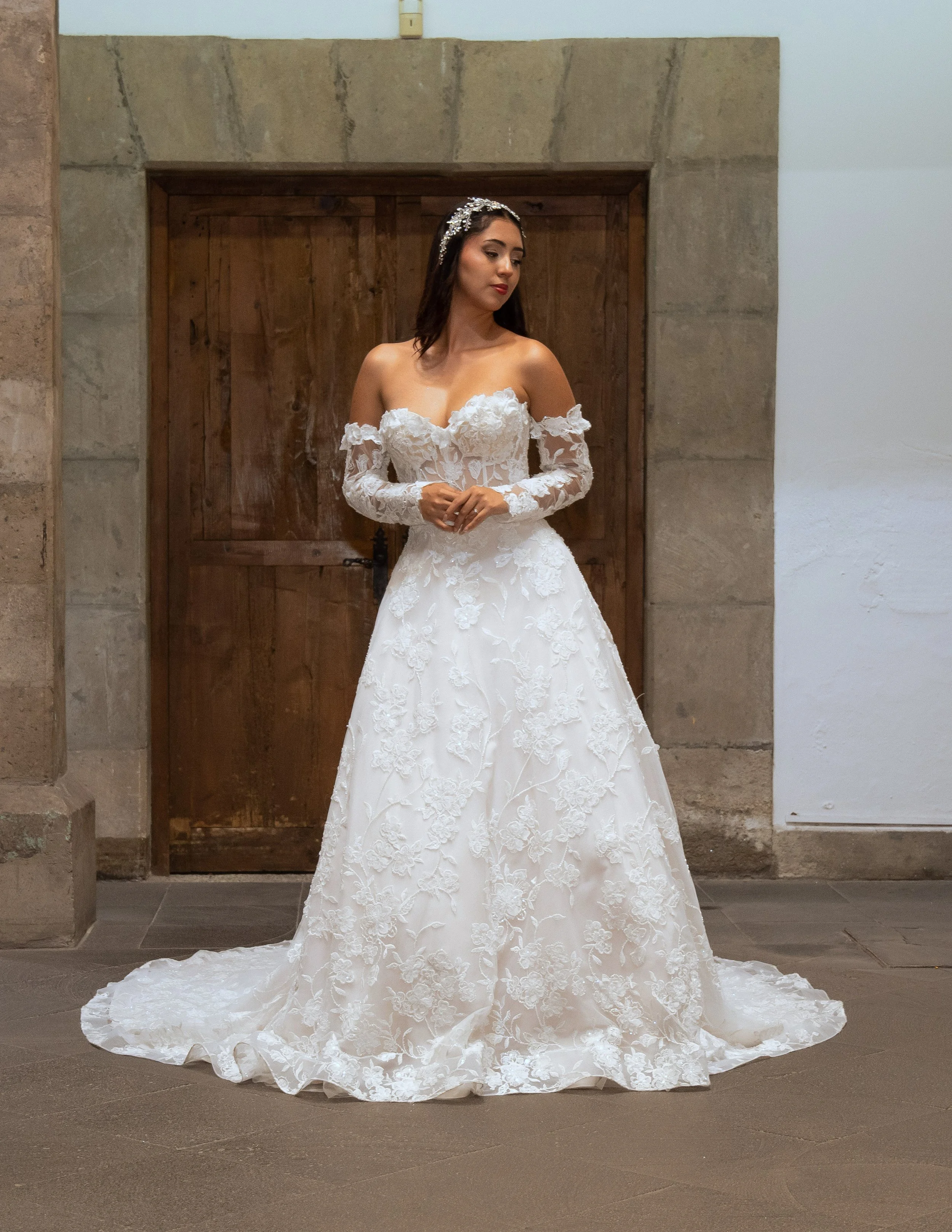 Novia con el vestido Lucas de Bridenformal, línea A de encaje con escote corazón y mangas largas desmontables, vista frontal completa.