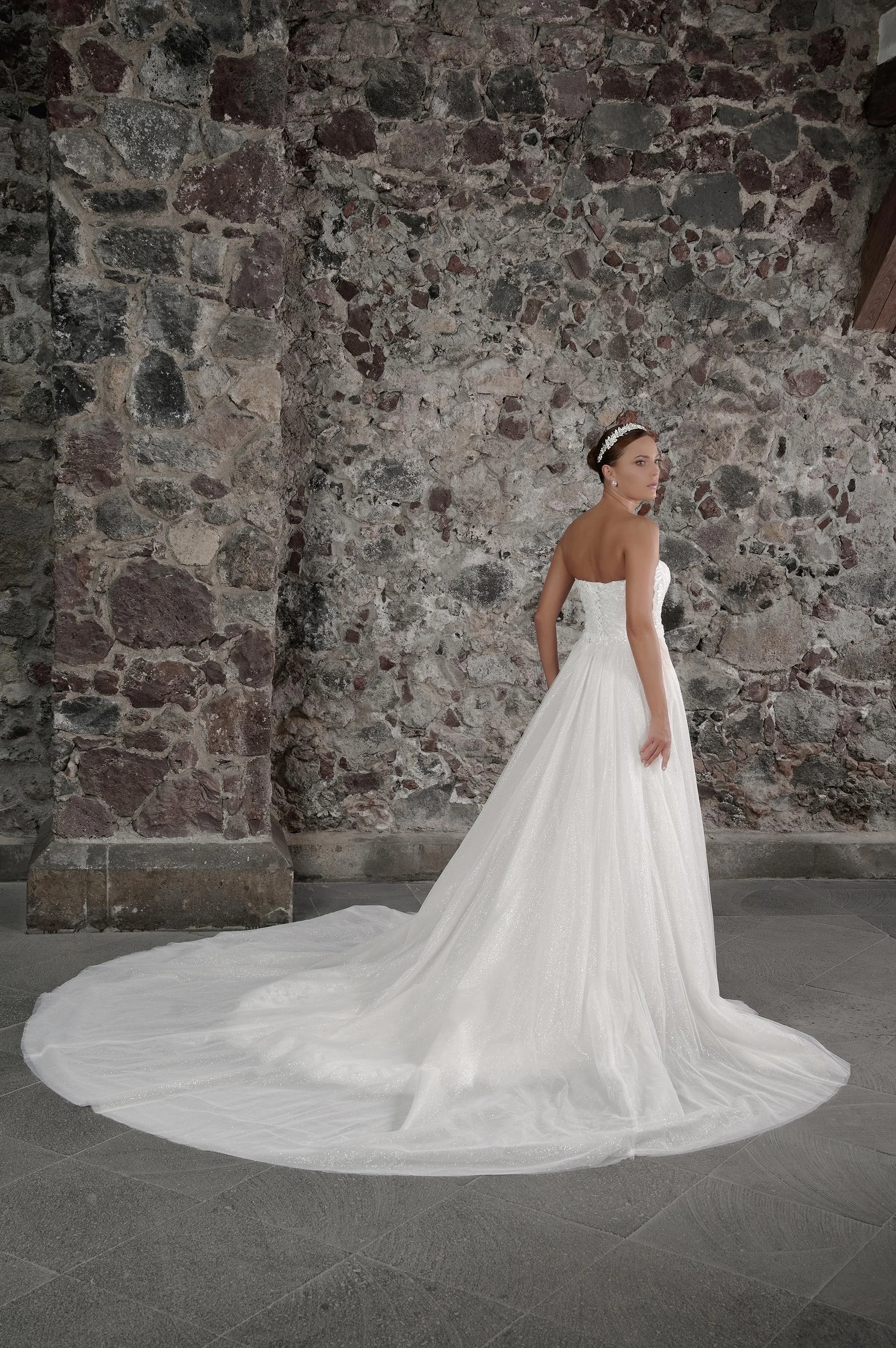 Espalda del vestido de novia Carolina con sobrefalda de tul brillante y cola larga.