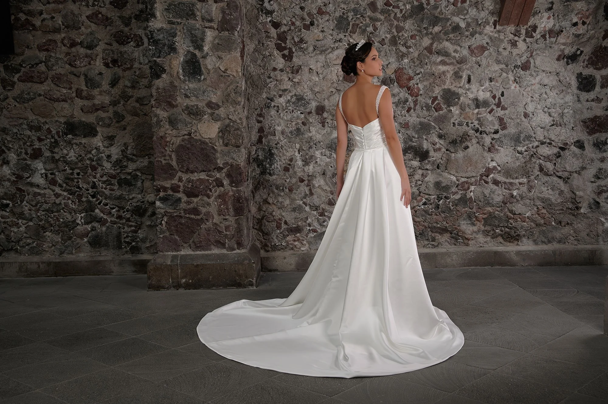 Espalda del vestido de novia Cian con la sobrefalda de satén desplegada y cola larga.
